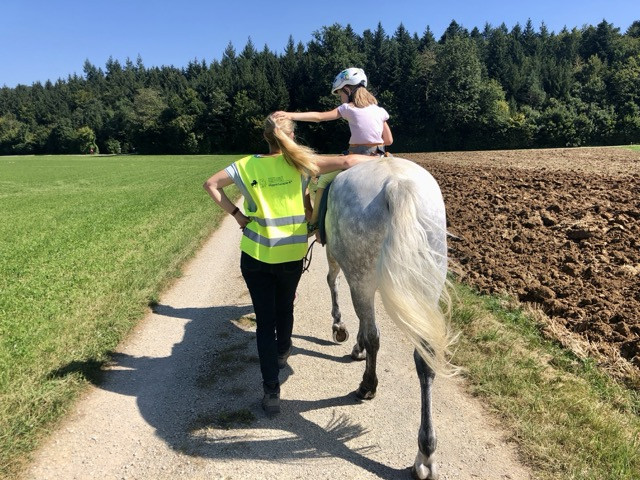 hippo1.jpg Ein Kind reitet ohne Sattel auf einem Pferd. Daneben läuft die Phystiotherapeutin